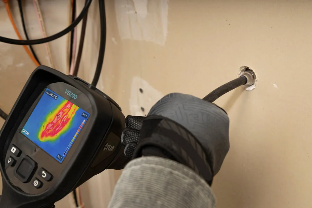 Sonda do videoscópio térmico FLIR VS290 inserida em um furo na parede para ver cabos por trás do acabamento